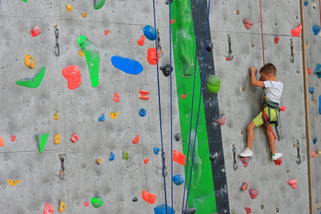 Young boy climbing up a climbing wall, typical of what a family session offers