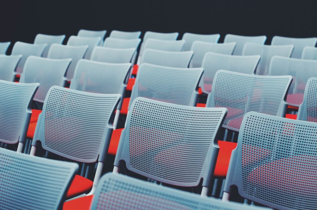 Rows of white chairs set out in an empty conference room, ready for a meeting