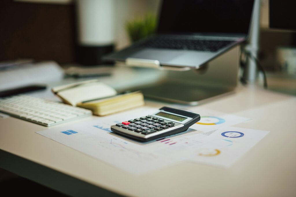 Calculator sitting on a table next to a laptop, representing bookkeeping for a small business