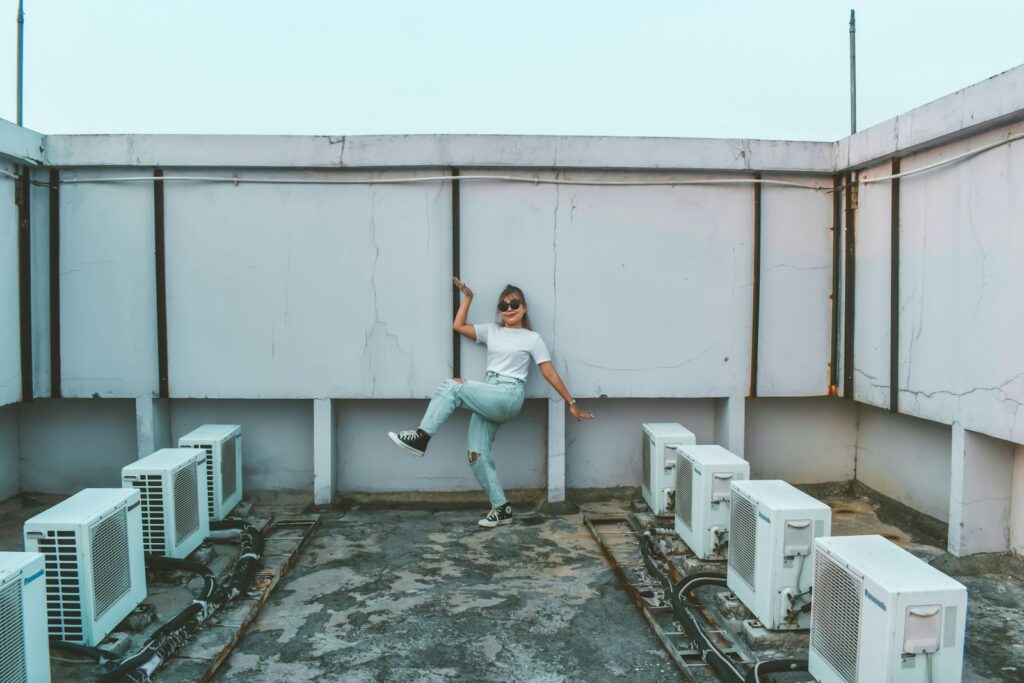Woman leaning against a wall in front of a bank of air conditioning units